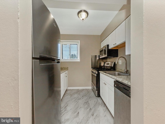 kitchen featuring baseboards, stainless steel appliances, marble finish floor, white cabinetry, and a sink