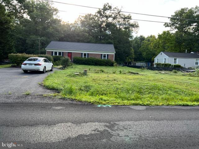 view of front of house with brick siding, a front yard, and driveway