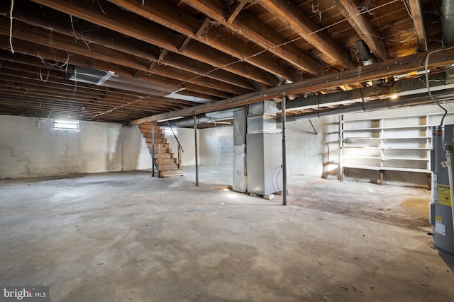 below grade area featuring heating unit, stairway, and electric water heater