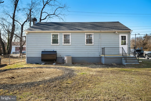 rear view of house with cooling unit, roof with shingles, a chimney, and fence