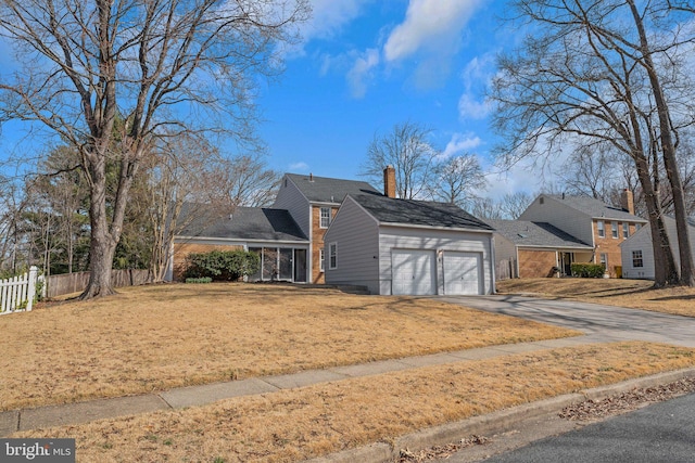 view of front of house with a front yard, a chimney, an attached garage, and fence