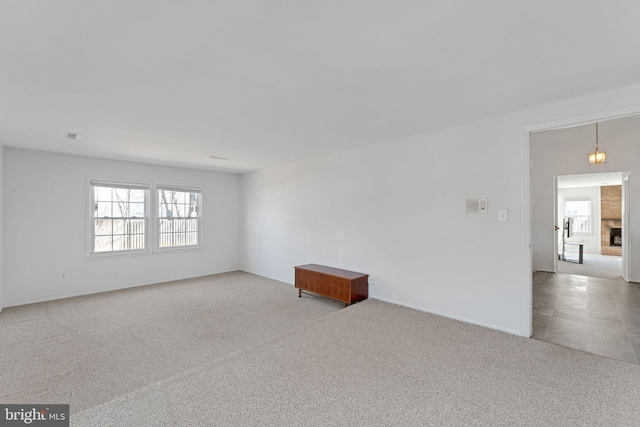 carpeted empty room with a fireplace and a healthy amount of sunlight