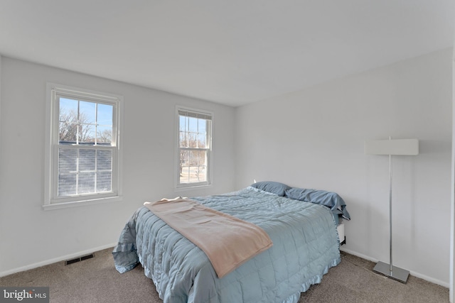 carpeted bedroom with multiple windows, baseboards, and visible vents