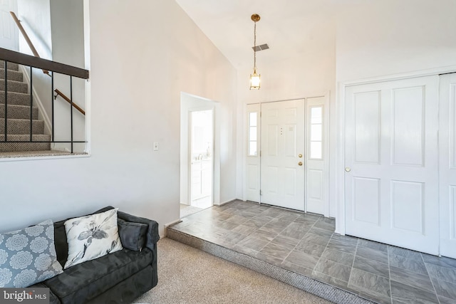 foyer entrance with stairway, visible vents, and high vaulted ceiling