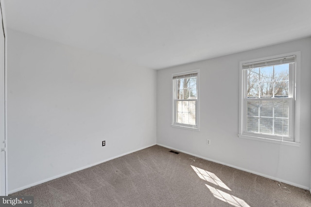 carpeted spare room featuring visible vents and baseboards