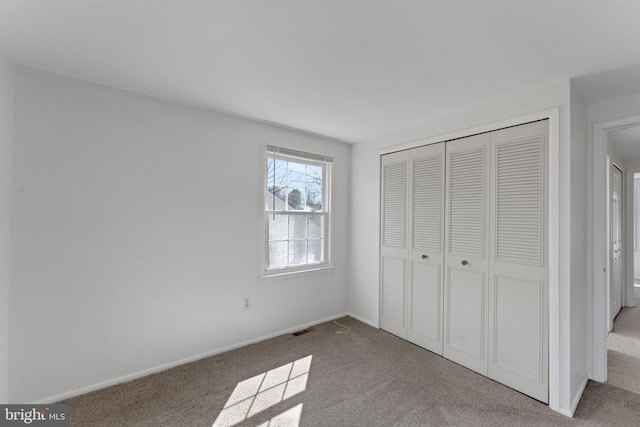 unfurnished bedroom featuring carpet flooring, visible vents, a closet, and baseboards