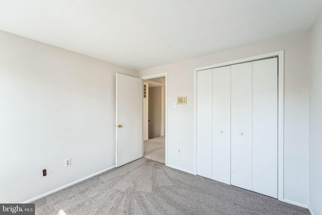 unfurnished bedroom featuring a closet, carpet floors, and baseboards