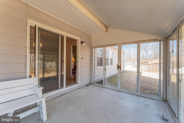 unfurnished sunroom featuring vaulted ceiling and plenty of natural light