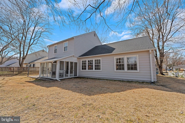 back of house with roof with shingles, fence, a yard, and a sunroom