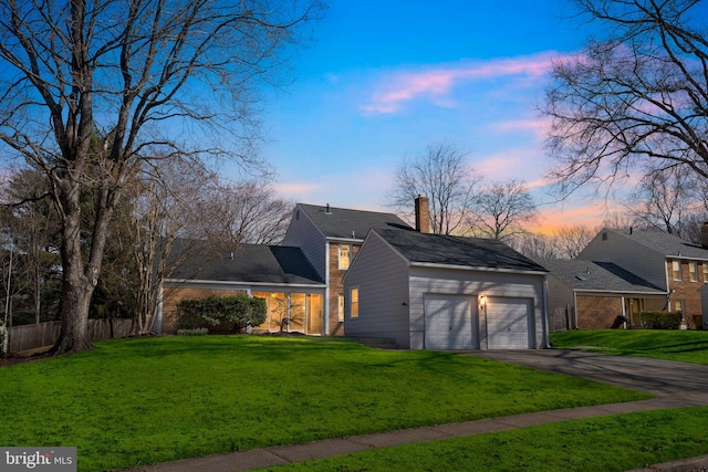 property exterior at dusk with aphalt driveway, a yard, an attached garage, and a chimney