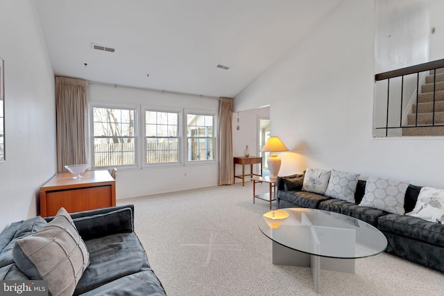 living area with stairway, carpet, visible vents, and high vaulted ceiling