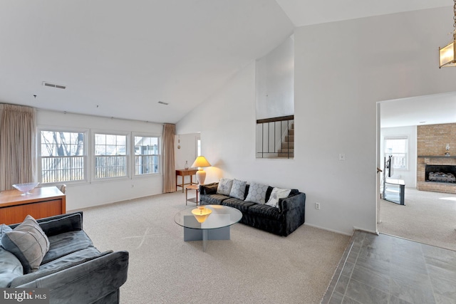 living area featuring visible vents, baseboards, carpet floors, a fireplace, and high vaulted ceiling