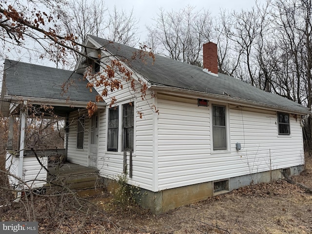 view of home's exterior with roof with shingles and a chimney