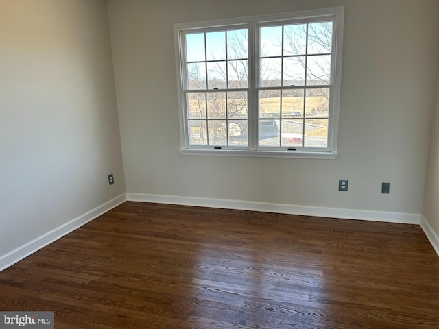 empty room featuring dark wood finished floors and baseboards