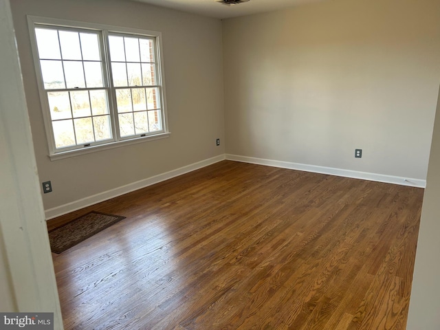 spare room with visible vents, dark wood-type flooring, and baseboards