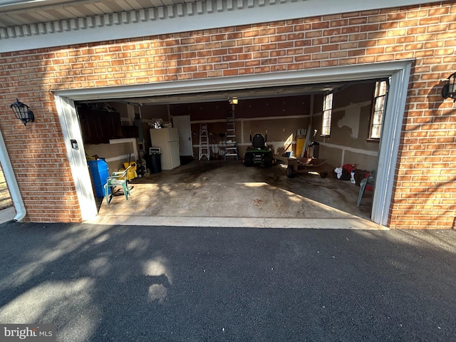 garage with driveway and freestanding refrigerator