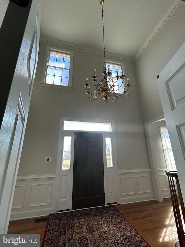 foyer featuring a decorative wall, plenty of natural light, wood finished floors, and ornamental molding