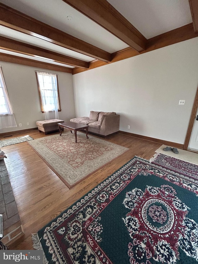 living area with beamed ceiling, baseboards, and wood finished floors