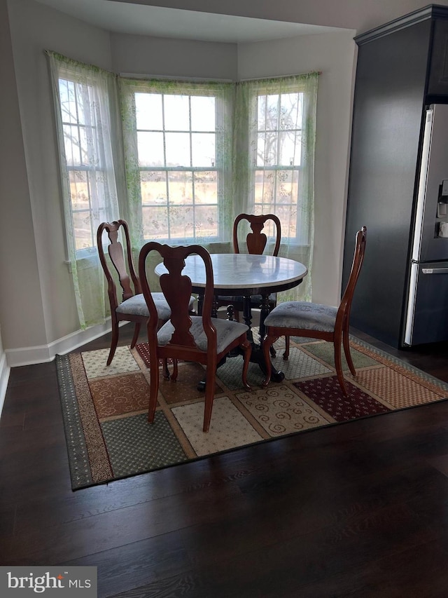 dining space featuring dark wood finished floors and baseboards