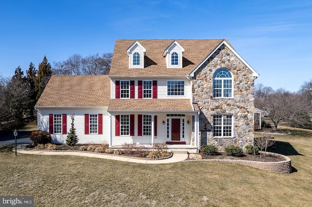 view of front facade featuring stone siding, a porch, a shingled roof, and a front lawn