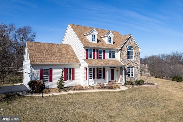 view of front of property featuring stone siding, covered porch, a front lawn, and roof with shingles