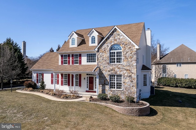 view of front of house with stone siding, a shingled roof, and a front yard