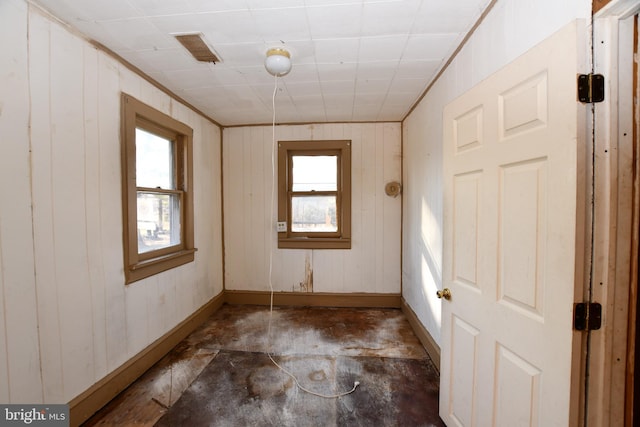 unfurnished room with visible vents, baseboards, and wooden walls