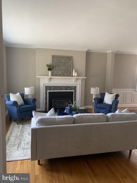 living room with wood finished floors, a fireplace, and ornamental molding