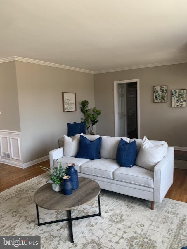 living room featuring baseboards, wood finished floors, and crown molding