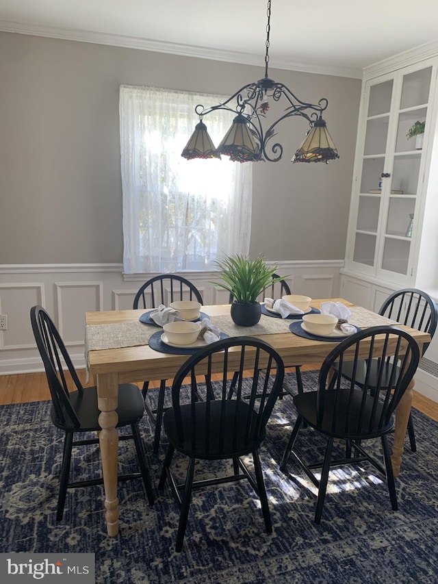 dining area featuring a wainscoted wall, crown molding, and wood finished floors