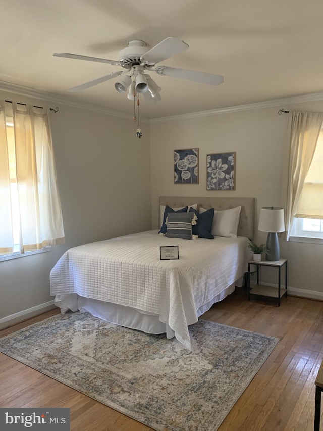 bedroom with ceiling fan, wood finished floors, baseboards, and ornamental molding