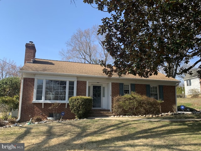 view of front of house with a front lawn, brick siding, a chimney, and entry steps