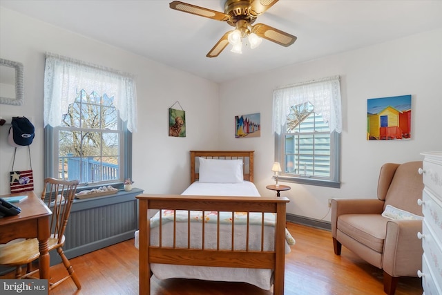 bedroom featuring radiator heating unit, a ceiling fan, and wood finished floors