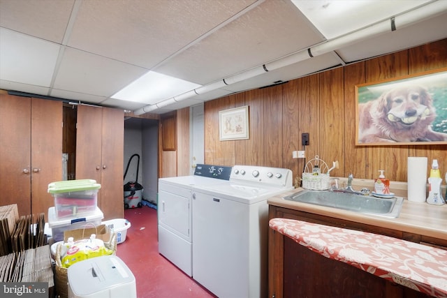 washroom with independent washer and dryer, wood walls, and a sink