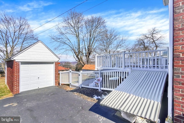 view of yard with fence, aphalt driveway, a garage, a deck, and an outdoor structure