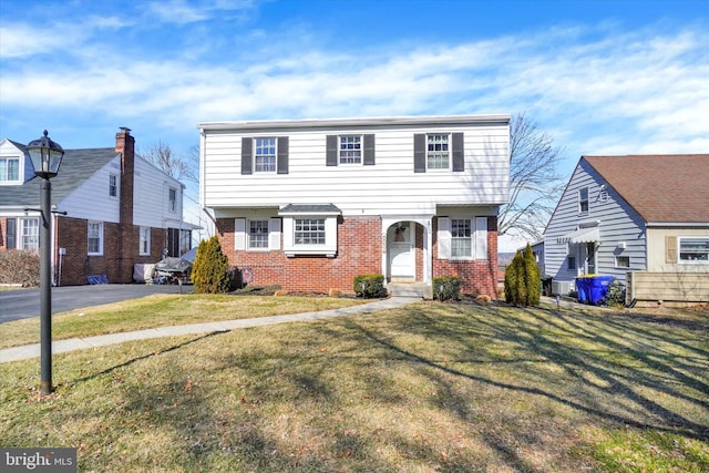 colonial home featuring a front lawn and brick siding