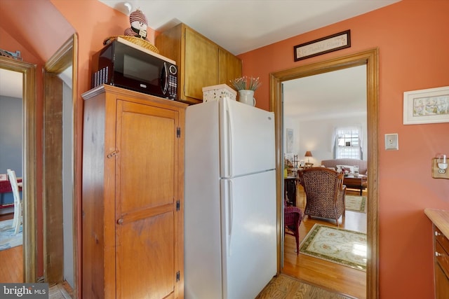 kitchen with light wood-type flooring, freestanding refrigerator, and black microwave