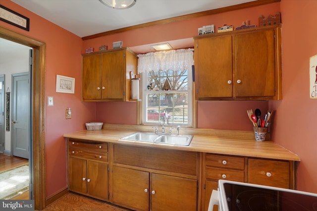 kitchen with light countertops, brown cabinets, electric range oven, and a sink