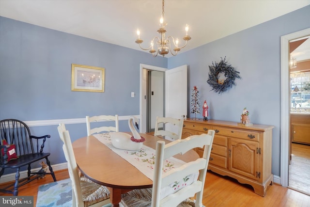 dining area featuring baseboards, an inviting chandelier, and light wood finished floors