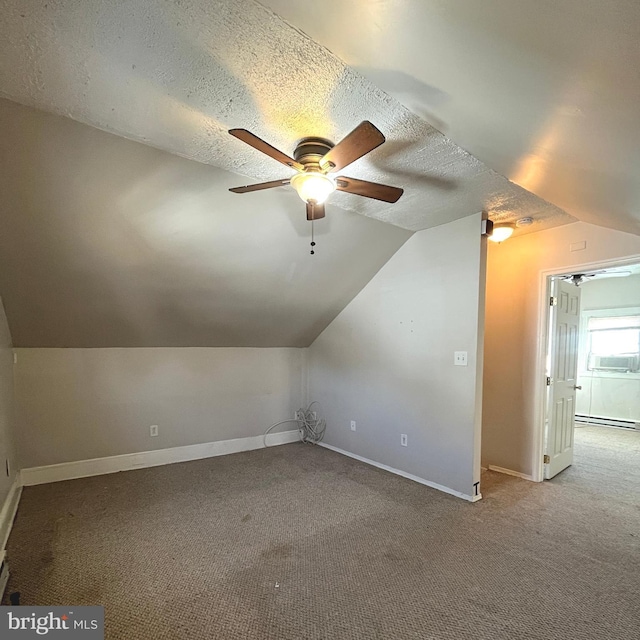 additional living space with ceiling fan, baseboards, vaulted ceiling, carpet flooring, and a textured ceiling