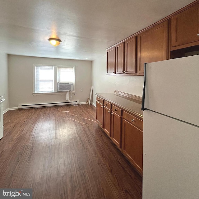 kitchen with dark wood-type flooring, baseboards, brown cabinets, freestanding refrigerator, and a baseboard radiator