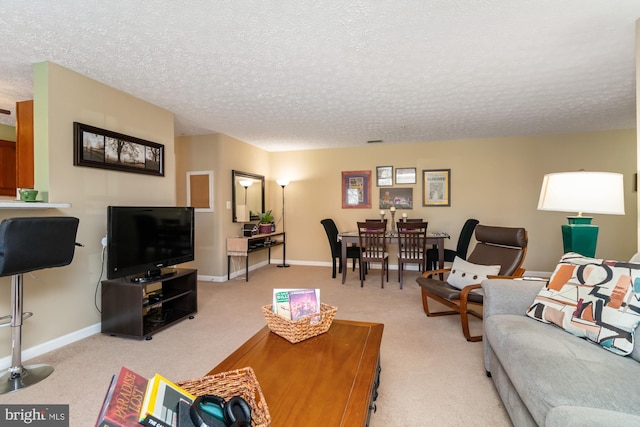 living area with light carpet, a textured ceiling, and baseboards