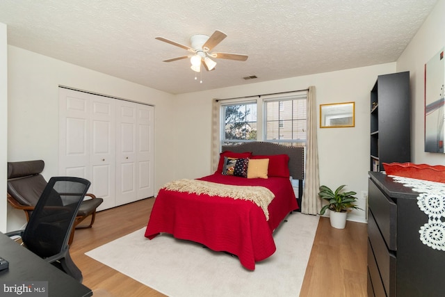 bedroom with a closet, visible vents, a textured ceiling, and wood finished floors