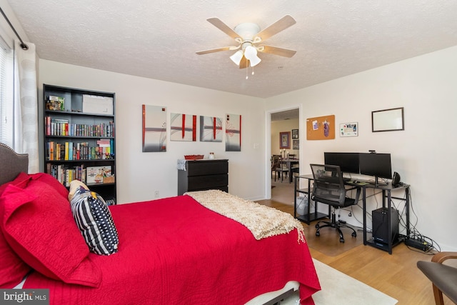 bedroom with ceiling fan, a textured ceiling, and wood finished floors