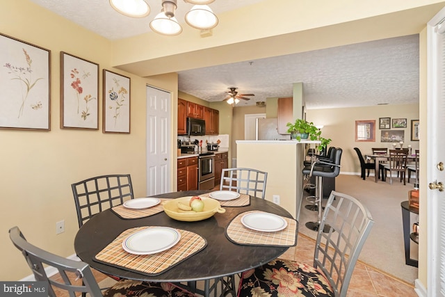 dining area featuring ceiling fan with notable chandelier, light colored carpet, a textured ceiling, and baseboards