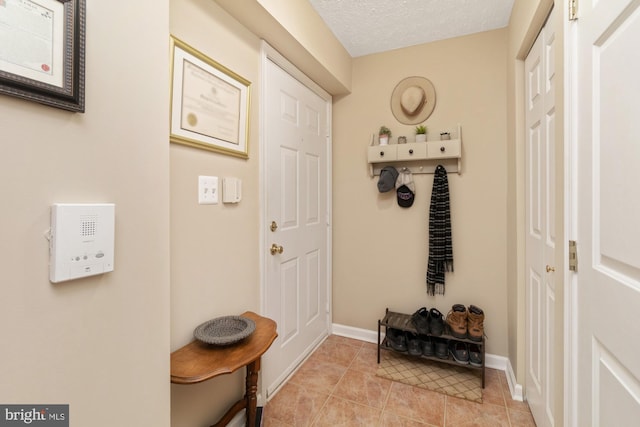 mudroom featuring light tile patterned flooring, a textured ceiling, and baseboards