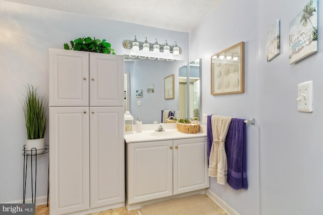 bathroom featuring baseboards, a textured ceiling, and vanity