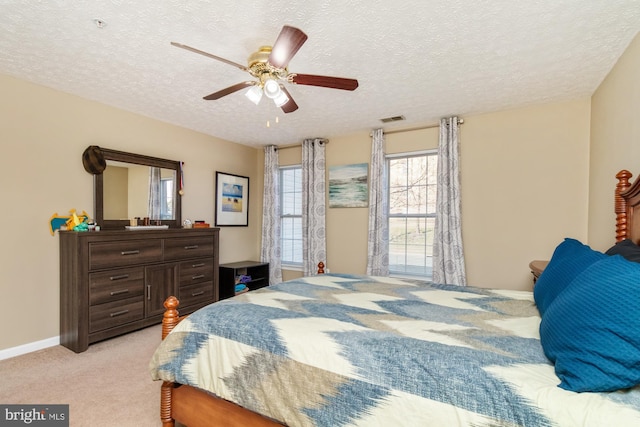 bedroom featuring visible vents, light carpet, a textured ceiling, baseboards, and ceiling fan