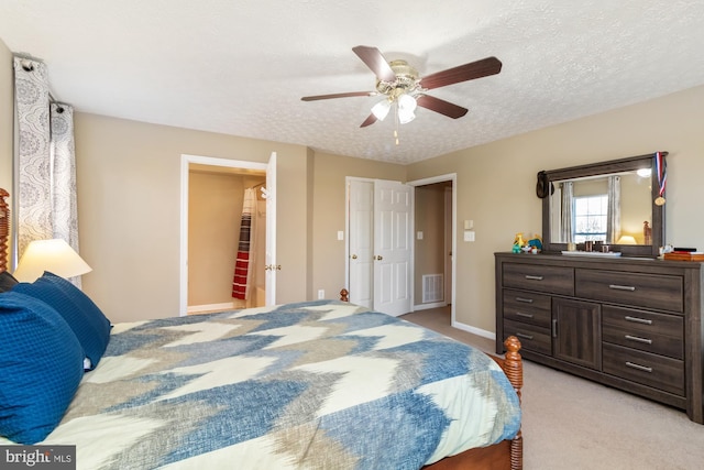 bedroom with light carpet, visible vents, a textured ceiling, and ceiling fan