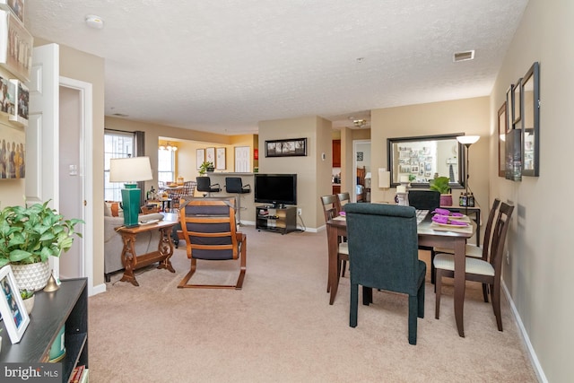 dining room featuring visible vents, light carpet, a textured ceiling, and baseboards